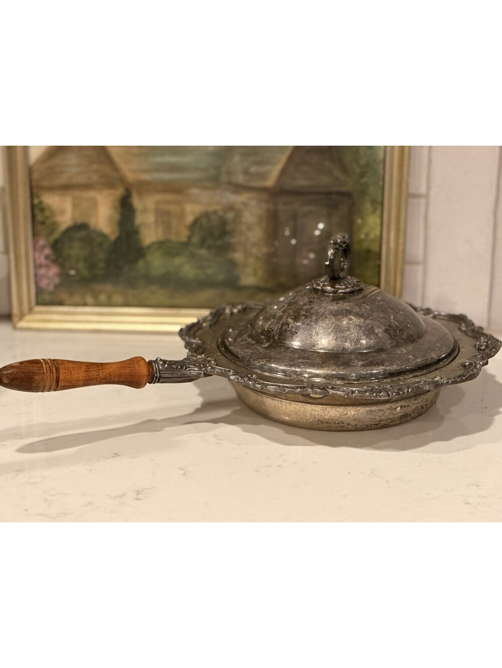 Ornate towlesilver-plated chafing dish with wooden handle and lid.